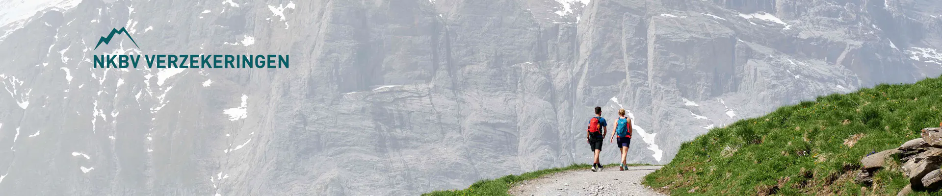 Twee wandelaars lopen over een pad aan de voet van een grote berg, met het logo van NKBV Verzekeringen.