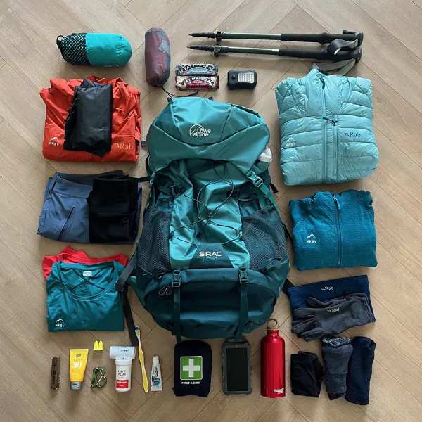 Wandeluitrusting voor een huttentocht, overzichtelijk uitgestald met rugzak, kleding en essentiële benodigdheden.